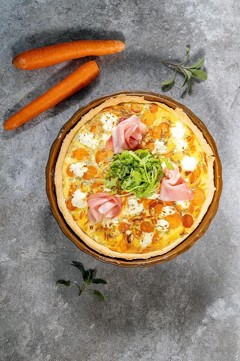 Carrot and goat cheese quiche with ham and arugula